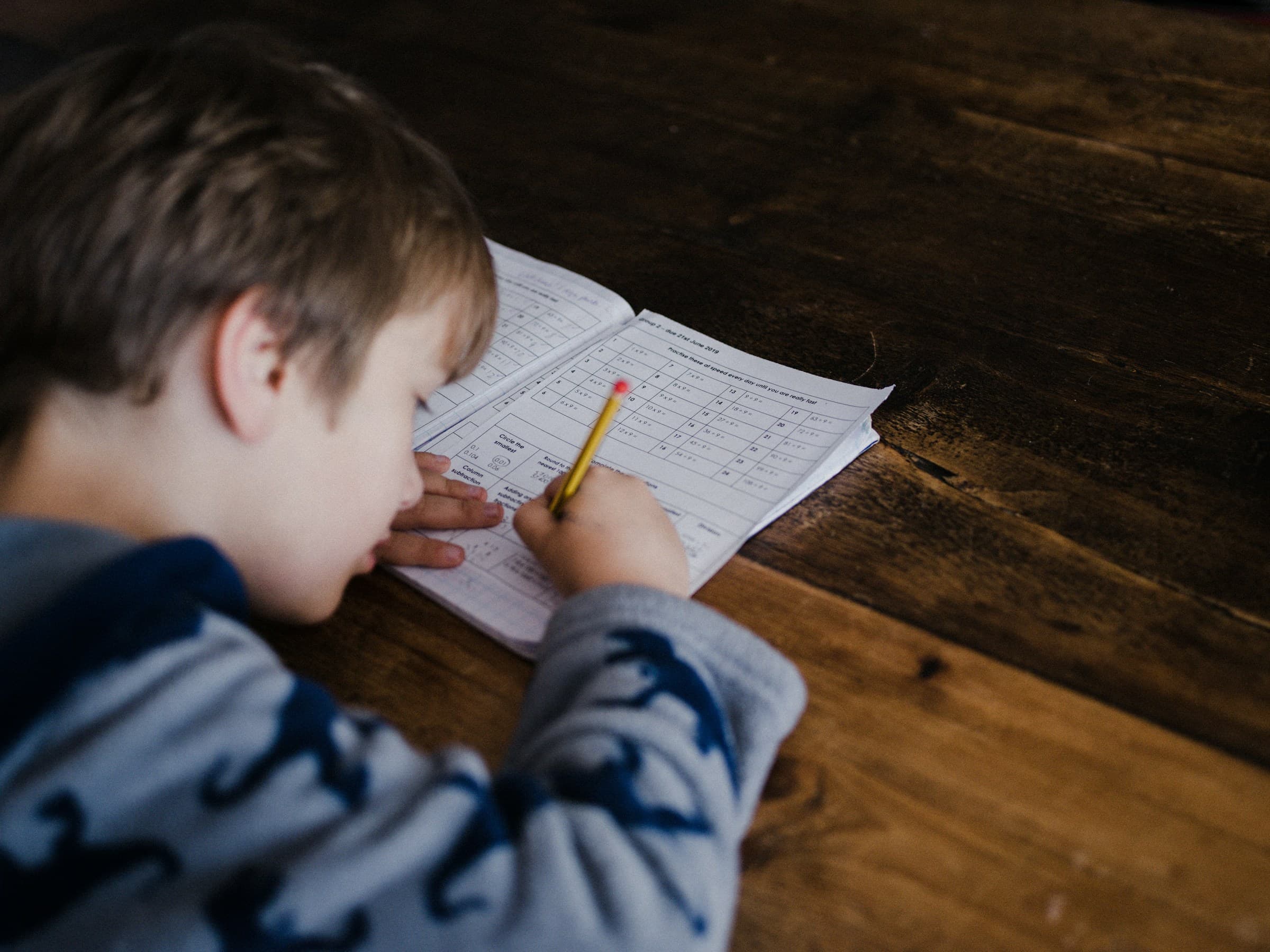 A young boy writing carefully in a lined exercise book