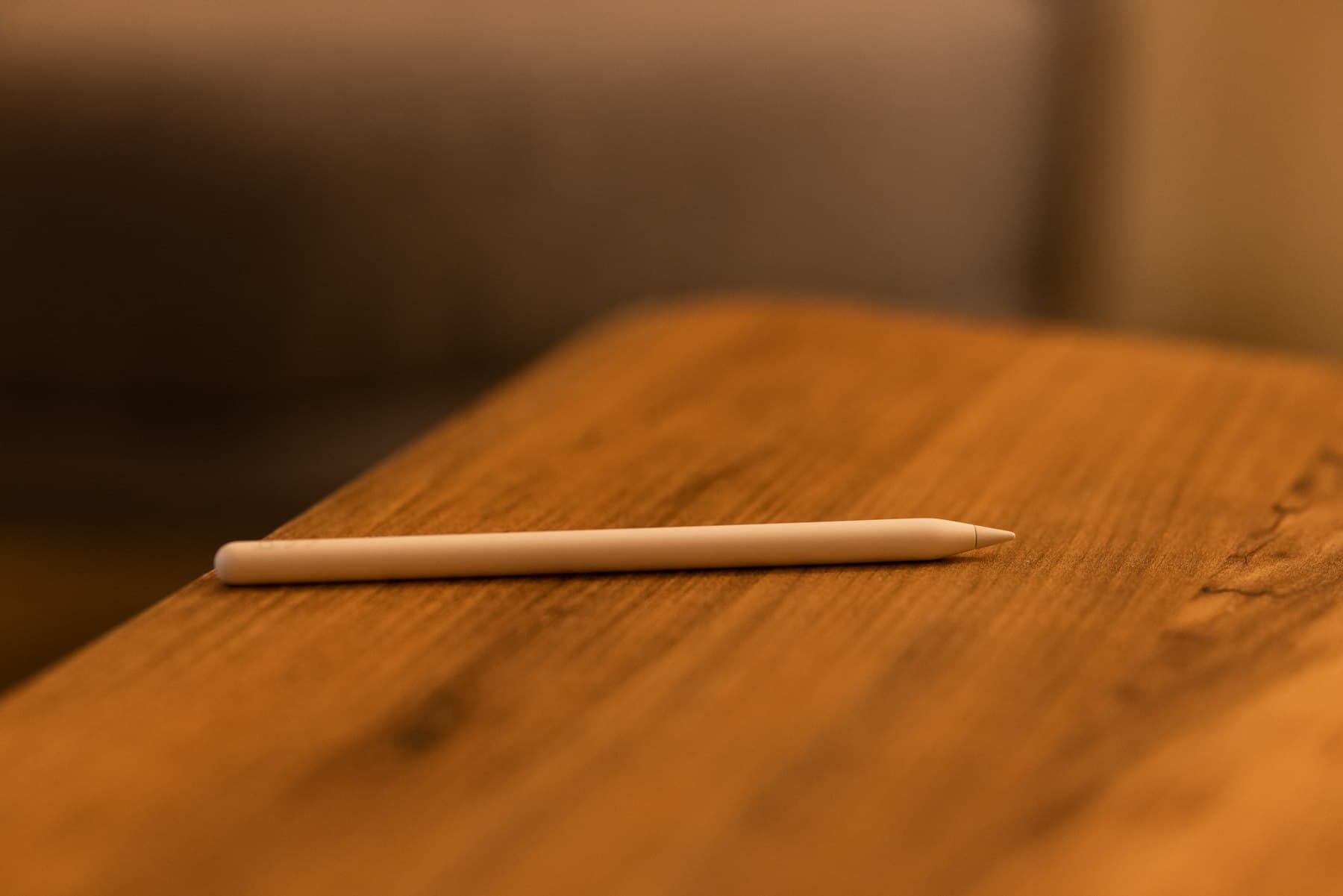 A single sharpened pencil resting on a warm wooden surface
