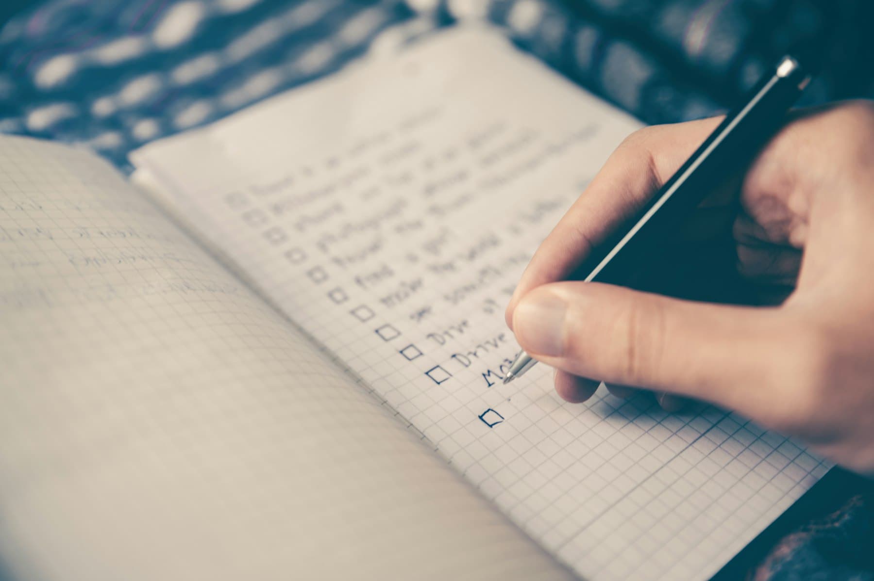 A hand writing with a pencil in a ruled notebook